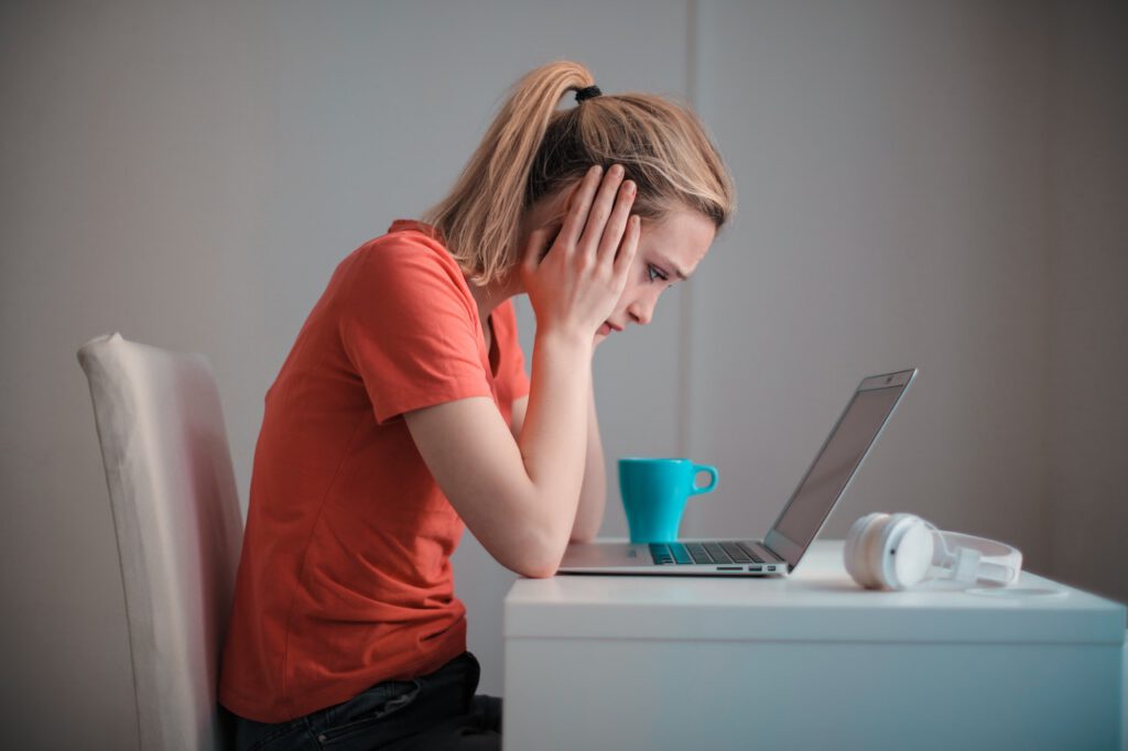 A distressed woman reading something on a laptop representing a person receiving an unfavourable Notice of Assessment from the CRA