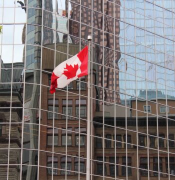 A Canadian flag next to an office tower representing an expansion of CEWS