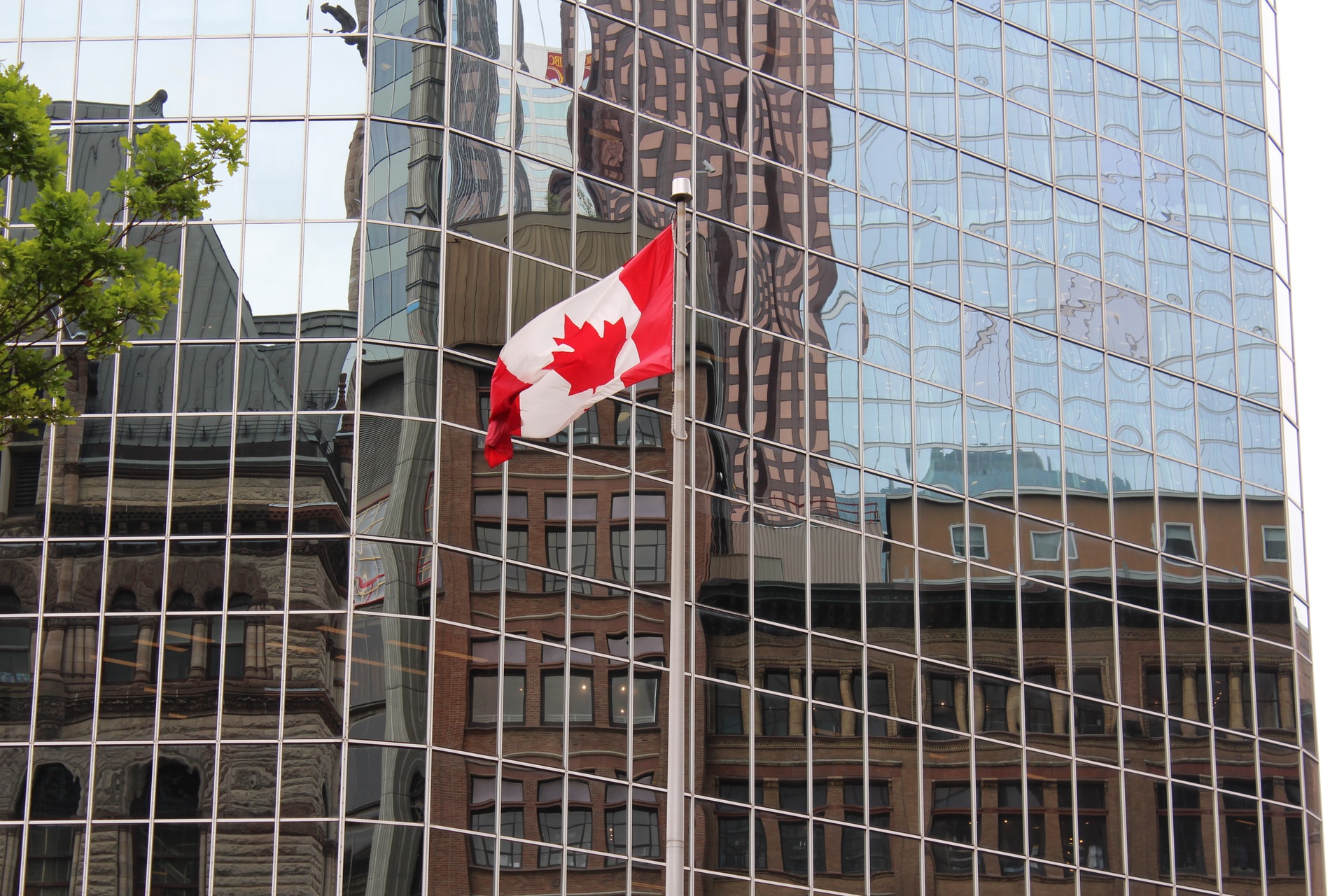 A Canadian flag next to an office tower representing an expansion of CEWS