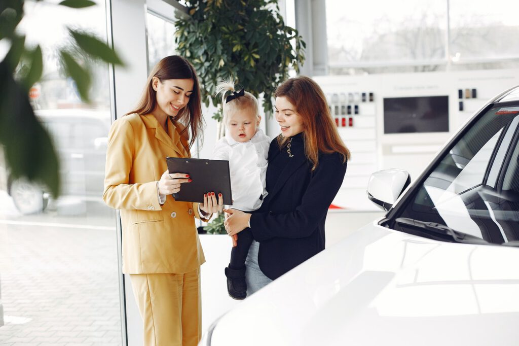 A woman buying a new car representing the question of whether to lease or buy