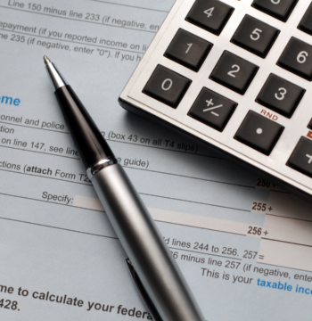 An image of a calculator and a pen on top of a small business owners tax form.