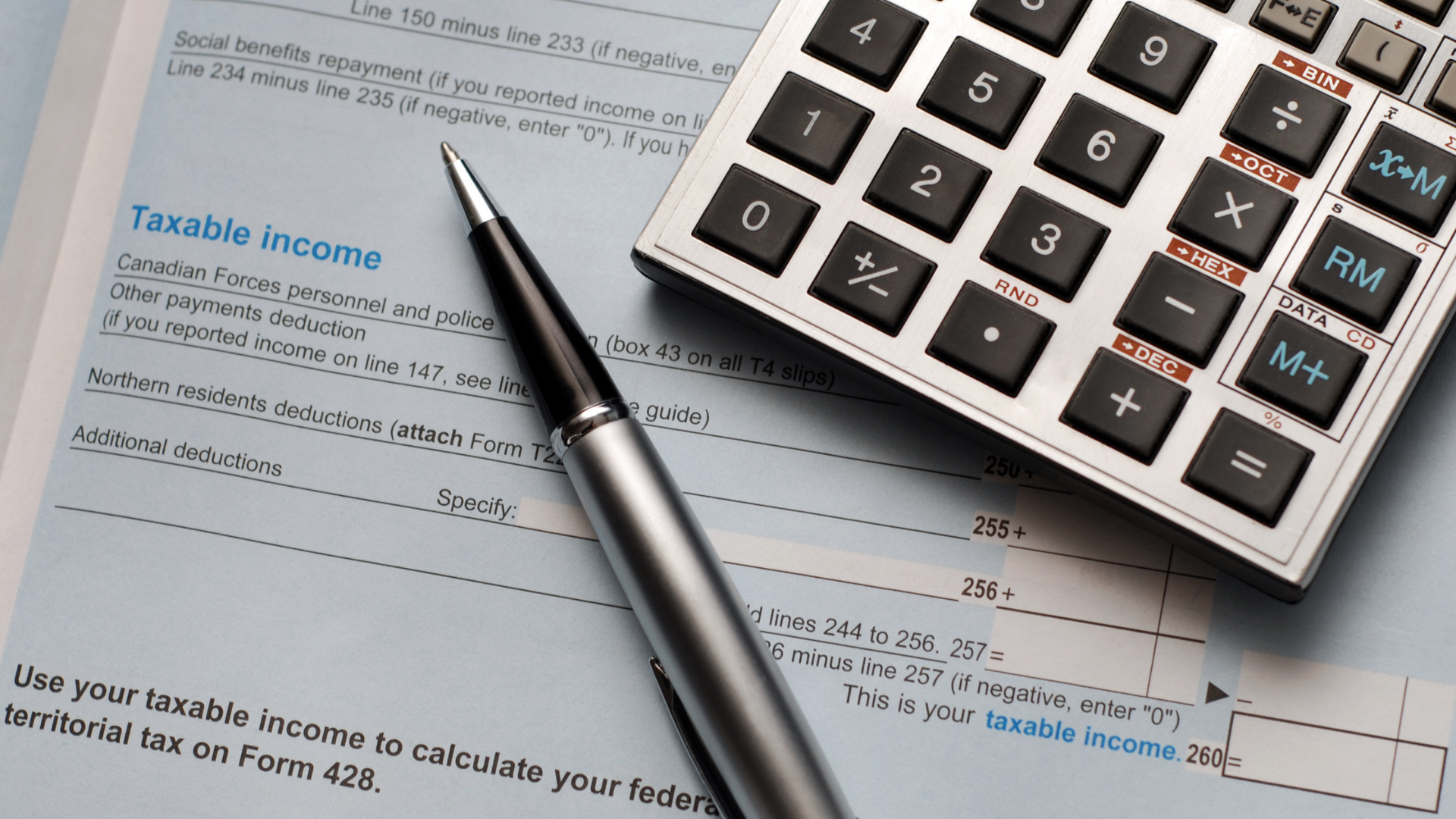 An image of a calculator and a pen on top of a small business owners tax form.