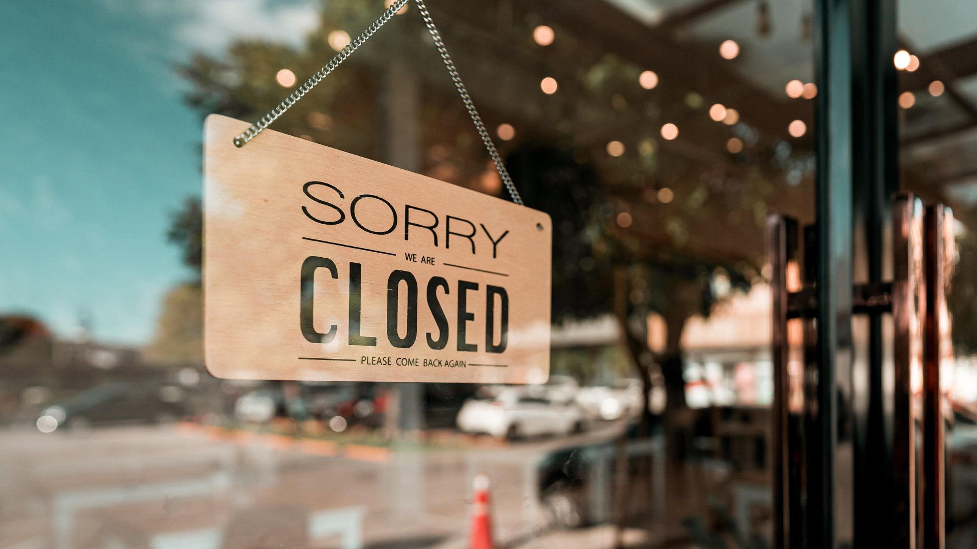 An image of a small business strorefront with a sign stating that it is closed.