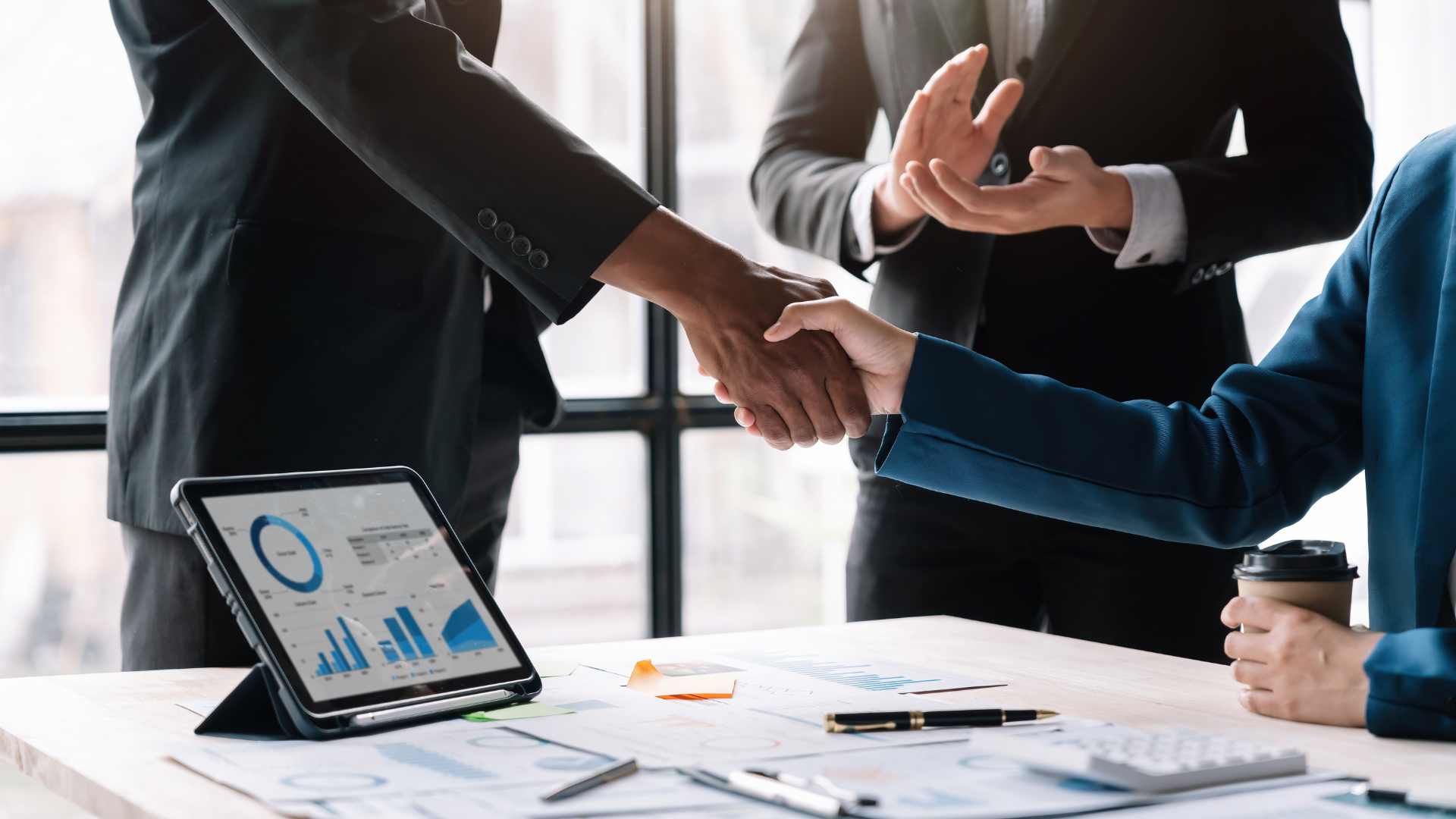 An image of some small business owners in Burlington Ontario who just completed a mergers and acquisition with their partner and are shaking hands.